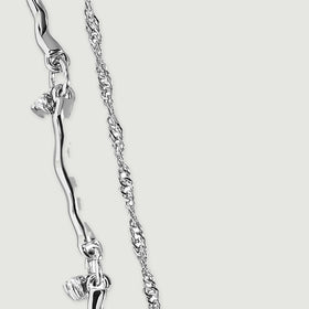 A close view of silver curved links reveals connecting rings and a small clear stone drop.