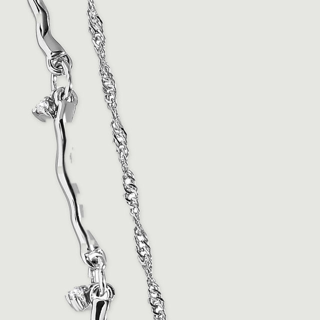 A close view of silver curved links reveals connecting rings and a small clear stone drop.