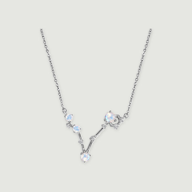 The sterling silver necklace has a V-shaped arrangement of four round moonstones and small clear accents on a light gray background.