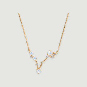 The yellow gold vermeil necklace has a V-shaped arrangement of four round moonstones and small clear accents on a light gray background.