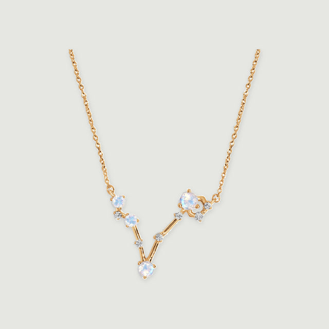 The yellow gold vermeil necklace has a V-shaped arrangement of four round moonstones and small clear accents on a light gray background.