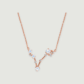 The rose gold vermeil necklace has a V-shaped arrangement of four round moonstones and small clear accents on a light gray background.