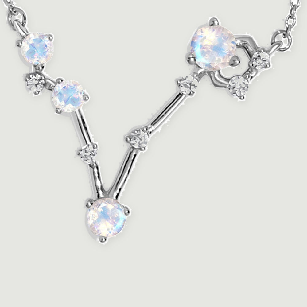 Four round moonstones and small clear accents form a silver V-shaped pendant between two sections of fine chain.