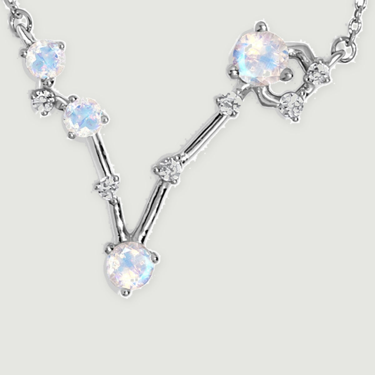 Four round moonstones and small clear accents form a silver V-shaped pendant between two sections of fine chain.