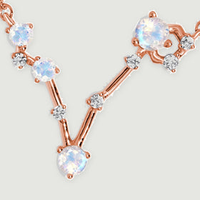 Rose gold connecting bars join round moonstones and tiny clear stones in an asymmetric V-shaped pendant.