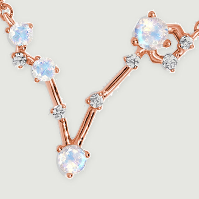 Rose gold connecting bars join round moonstones and tiny clear stones in an asymmetric V-shaped pendant.