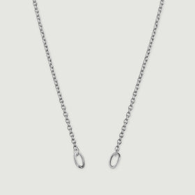 A fine silver chain descends in two strands with an oval ring at each end against a light gray background.