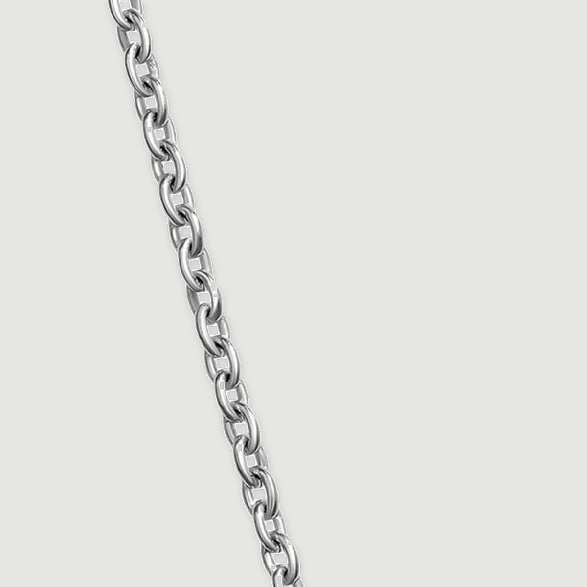 A diagonal length of fine silver chain reveals alternating open oval links on a clean gray surface.