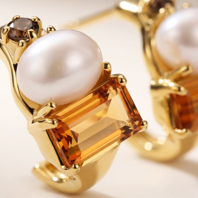 A close view shows a softly rounded pearl above a rectangular citrine held in yellow gold prongs.