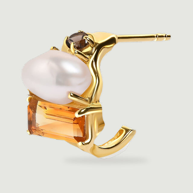 The side angle of a yellow gold earring reveals its open curved hoop and straight post behind the three-stone setting.