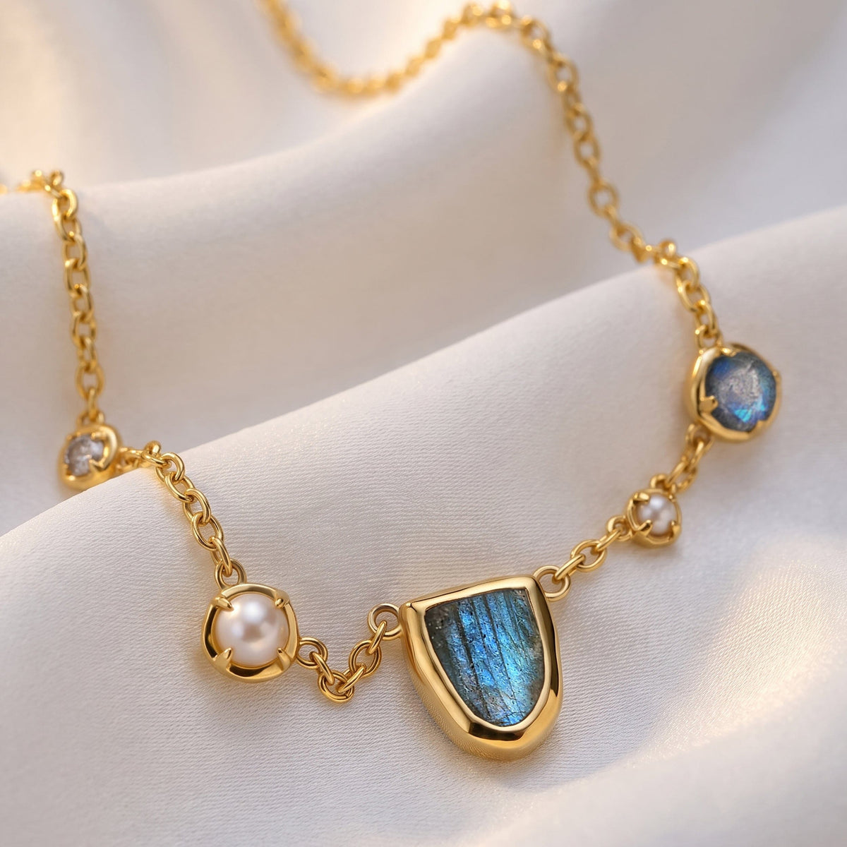 The gold-tone necklace lies on softly folded fabric with its blue stone and white pearls in view.