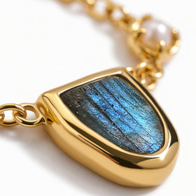 The blue labradorite centerpiece is shown close up with a polished gold-tone setting and oval chain links.