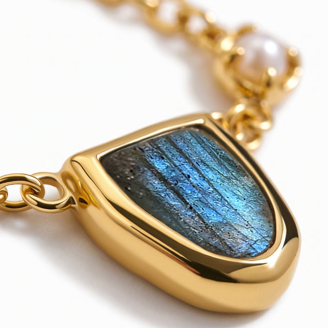 The blue labradorite centerpiece is shown close up with a polished gold-tone setting and oval chain links.
