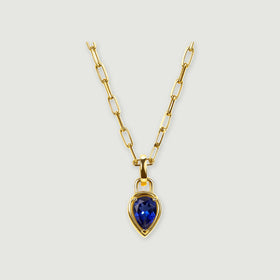 A pear-shaped deep-blue pendant hangs from a polished yellow-gold-tone rectangular-link chain on a light gray background.