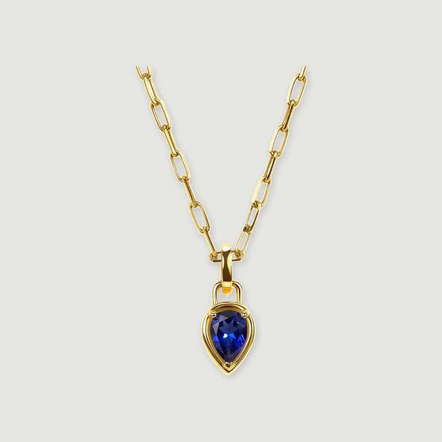 A pear-shaped deep-blue pendant hangs from a polished yellow-gold-tone rectangular-link chain on a light gray background.