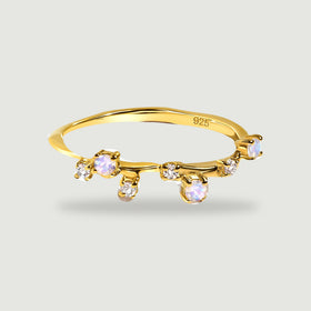 A yellow gold vermeil band displays pale round moonstones and smaller clear stones on a light gray background.