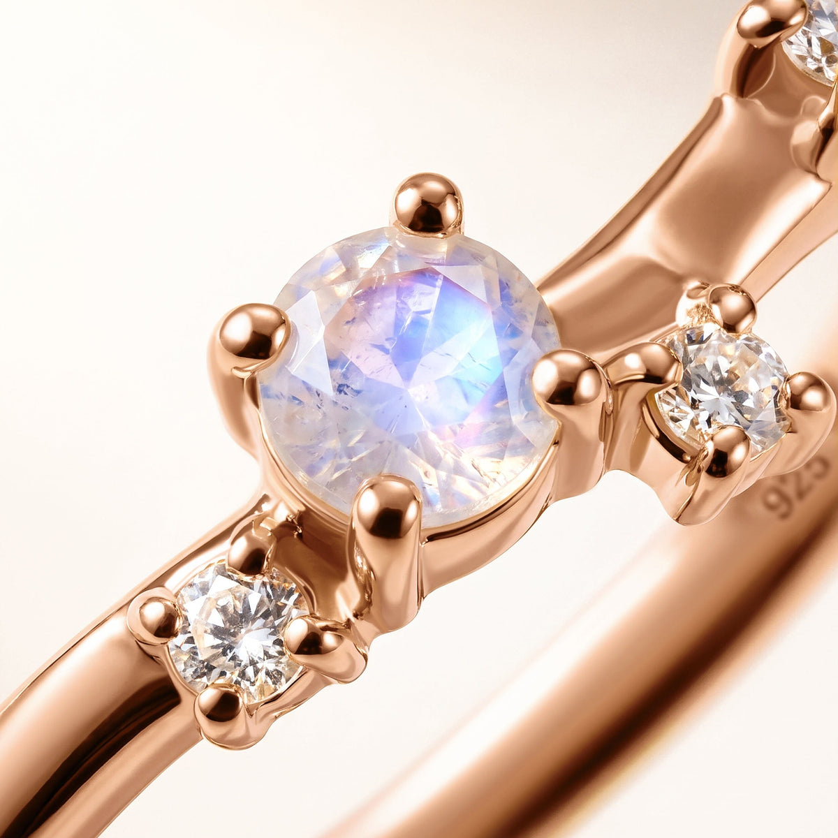 A diagonal close view reveals a pale blue moonstone, clear accents and polished rose gold vermeil prongs.
