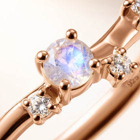 A diagonal close view reveals a pale blue moonstone, clear accents and polished rose gold vermeil prongs.