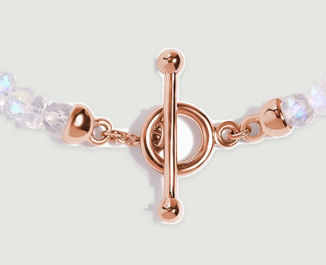 Rose gold links connect the round clasp and polished end caps to faceted pale moonstone beads.