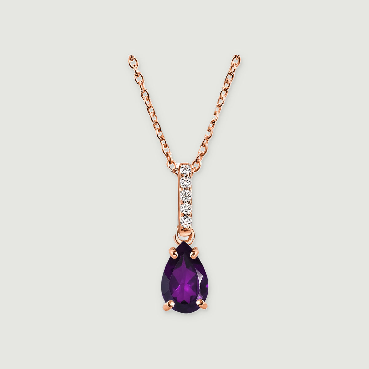 A rose gold vermeil necklace has a pear-shaped purple amethyst hanging beneath a vertical row of five clear stones on a light grey background.