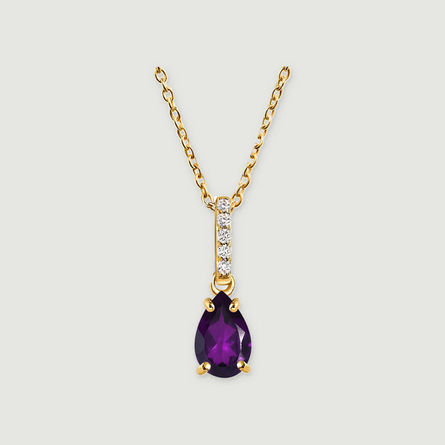 A yellow gold vermeil chain leads to a five-stone bail and a purple pear-shaped pendant centered on a light grey surface.