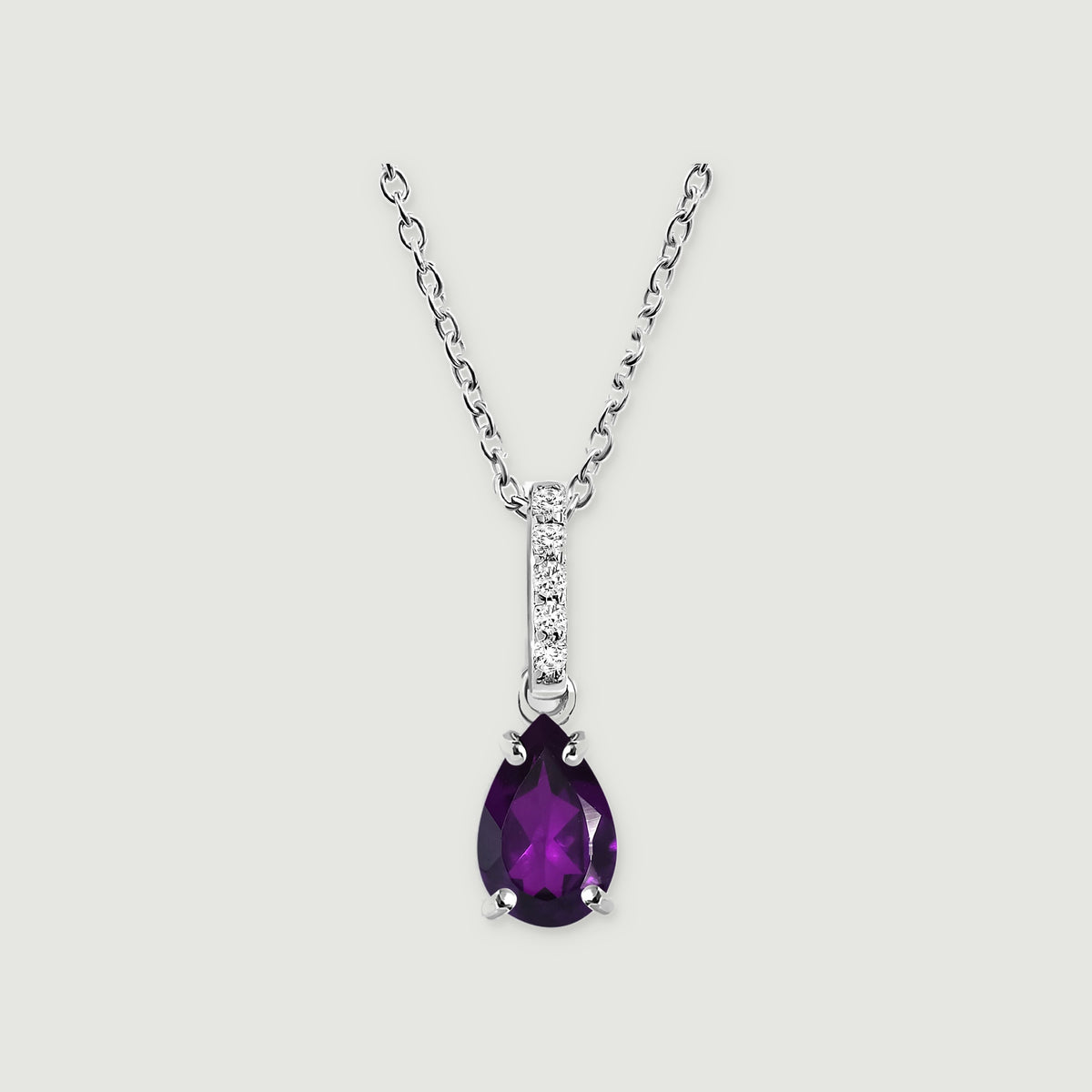 A sterling silver necklace displays a purple faceted pear pendant and five clear stones above an open connecting ring.