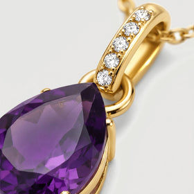 Five round clear stones line a yellow gold bail above the faceted purple amethyst in an angled close-up.