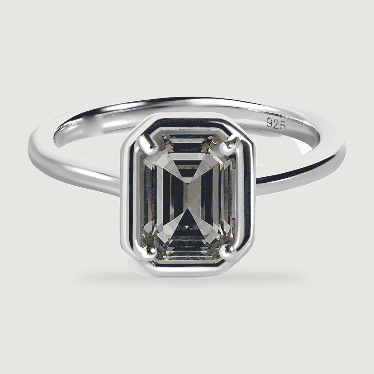 A grey emerald-cut stone shows dark stepped facets within a polished silver ring.