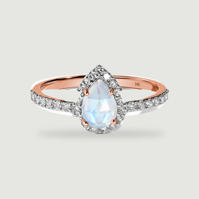 A rose gold ring displays a pale blue pear-shaped moonstone with a bright diamond border.