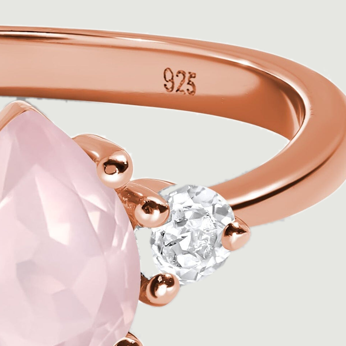 The right side of the rose gold ring shows its polished band, curved shoulder, and clear accent stone.
