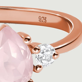 The right side of the rose gold ring shows its polished band, curved shoulder, and clear accent stone.