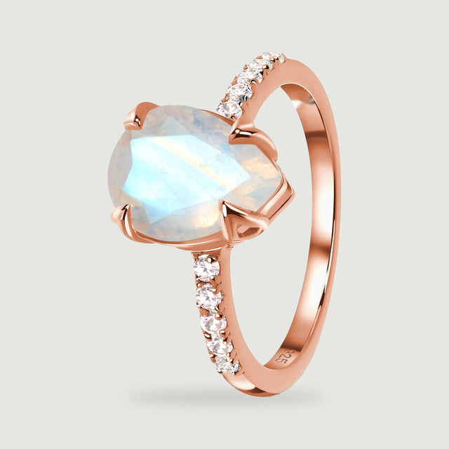 The rose gold vermeil ring is shown upright with pale blue reflections in the pear-shaped stone and a curved polished band.