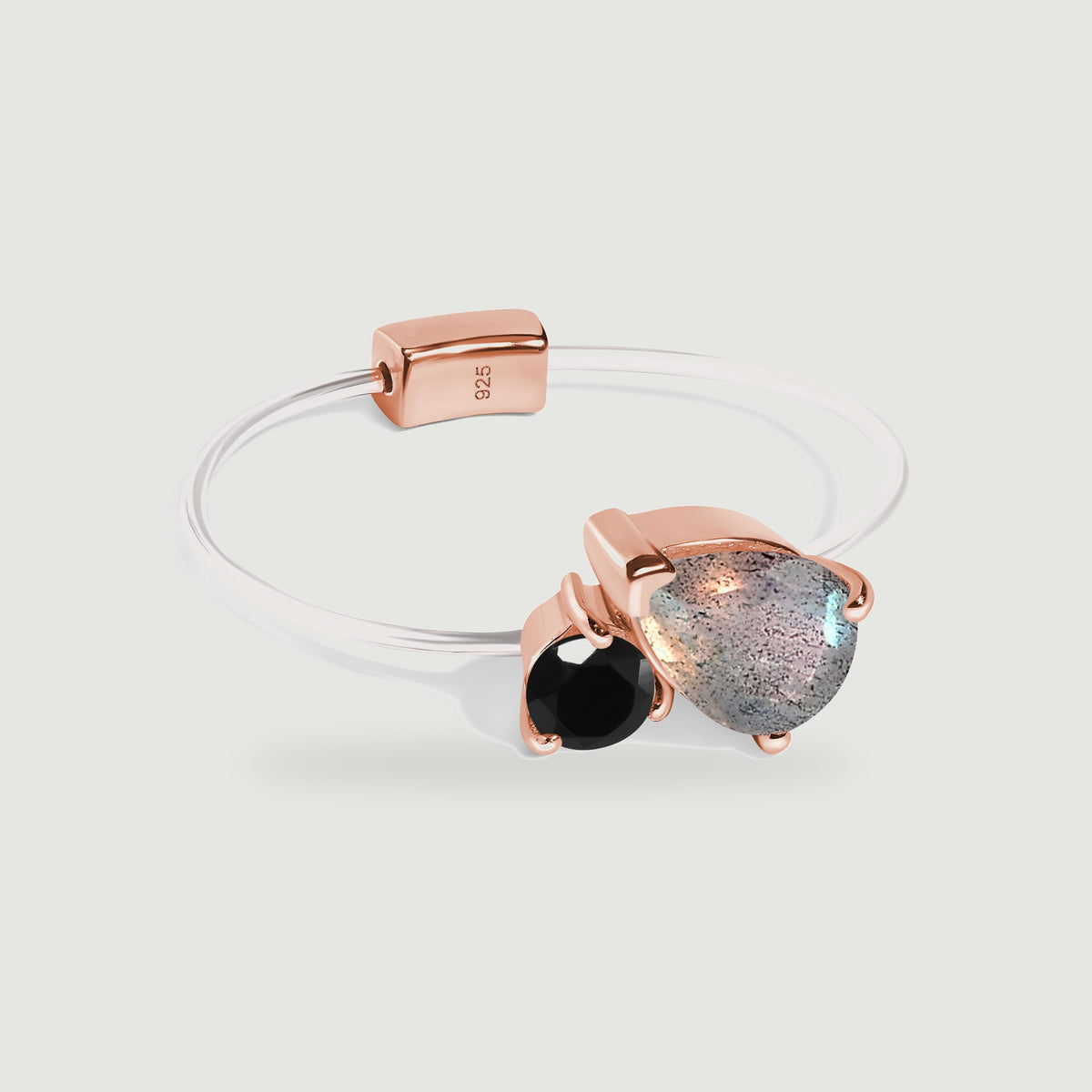 A rose gold vermeil ring pairs a pear-shaped grey labradorite with round black obsidian on a slender pale band.