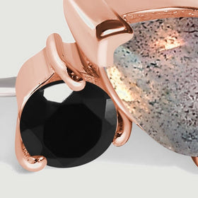 The faceted round black obsidian reflects light between curved rose gold prongs.