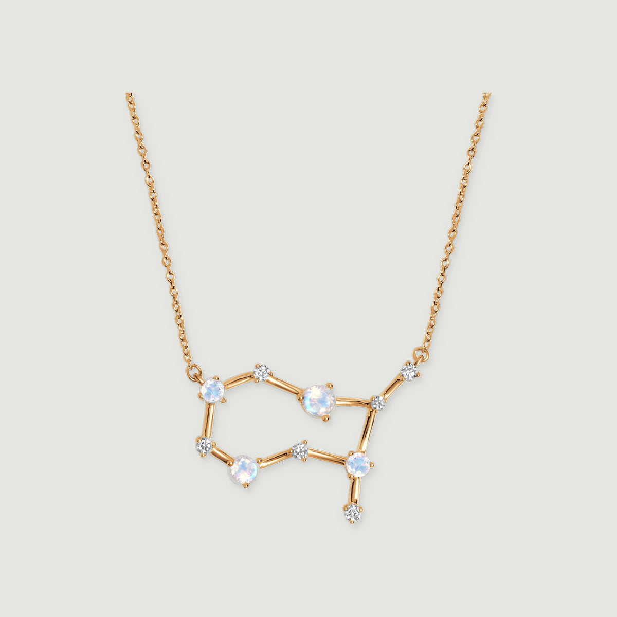 A yellow gold necklace displays an open geometric pendant with pale moonstones and clear stone accents.