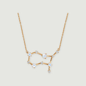 A yellow gold necklace displays an open geometric pendant with pale moonstones and clear stone accents.