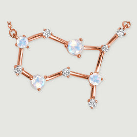A close view of the rose gold pendant reveals round moonstone facets, prongs, and tiny clear stones.