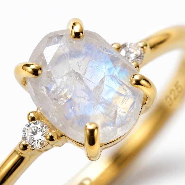 The textured moonstone and a faceted white zircon are held by polished yellow gold vermeil prongs in a tight detail view.