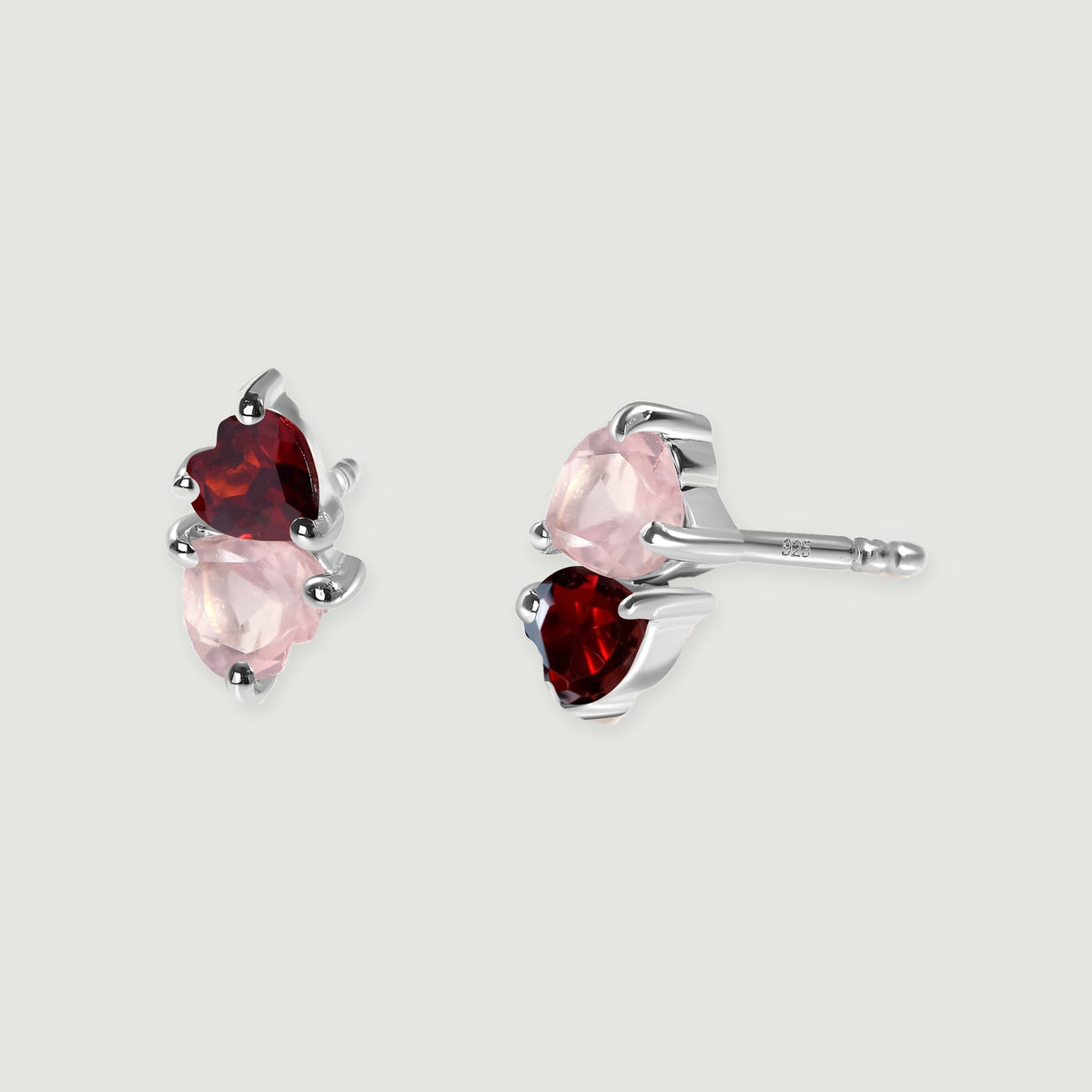 Two silver tone heart-stone earrings rest on a gray background with one straight post visible.