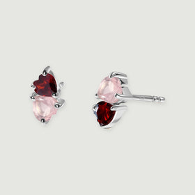 Two silver tone heart-stone earrings rest on a gray background with one straight post visible.