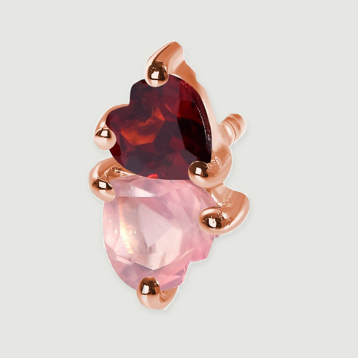A close view shows the facets of pink and burgundy hearts held by rose gold tone prongs.