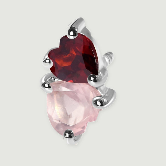 A close view shows pale pink and deep red heart-shaped stones gripped by polished silver tone prongs.