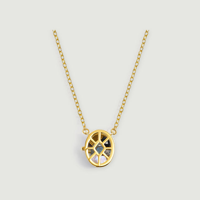 A yellow gold openwork oval locket with mixed gemstones and an oval-link chain is centered on a pale gray surface.