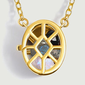 Yellow gold polished ribs frame gray, black, and translucent gemstones in this close view of the locket.