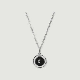 A sterling silver necklace shows a black circular pendant with a crescent inside an open polished ring.
