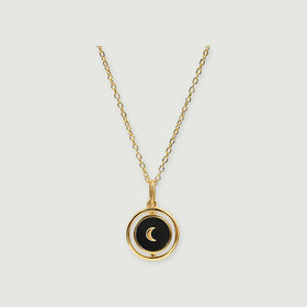 A yellow gold vermeil chain holds a round black onyx pendant with a gold crescent and a rotating outer frame.