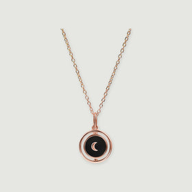 A rose gold vermeil necklace has a glossy black pendant with a matching crescent and circular surround.