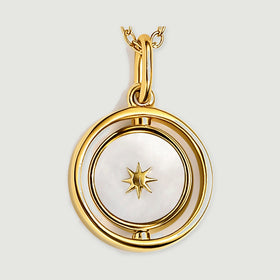 The yellow gold vermeil pendant is shown close up with a star on its pearly white face and a polished oval bail.