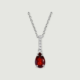 A silver chain holds a red pear-shaped pendant with four prongs and a vertical row of bright stones on light gray.