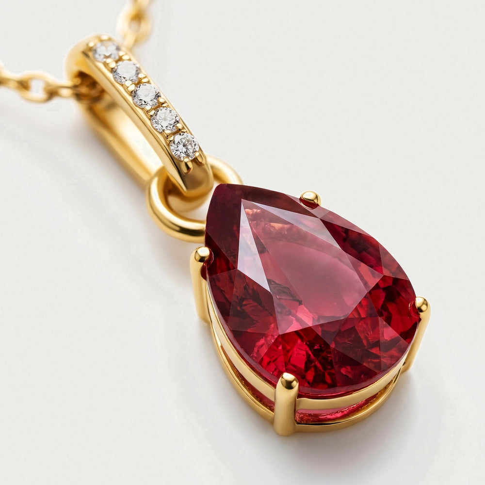 A close view shows the red pear-shaped gemstone, yellow gold prongs and five bright stones along the bail.
